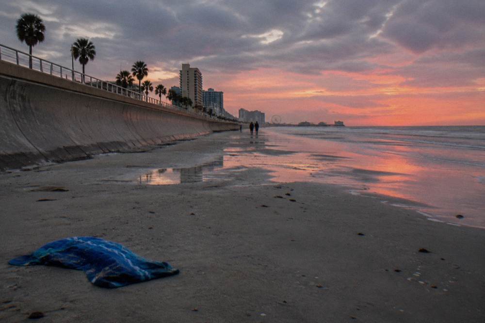 A long seawall promenade along the Gulf with calm water and an evening sky