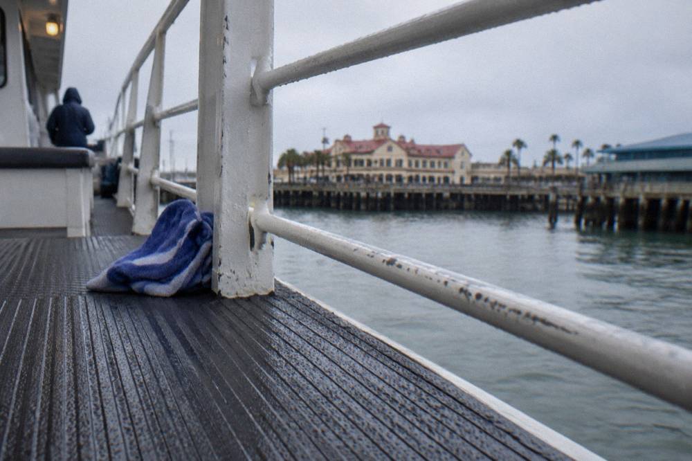 Close view of a boat deck with non-slip textured flooring and a rail overlooking harbor water