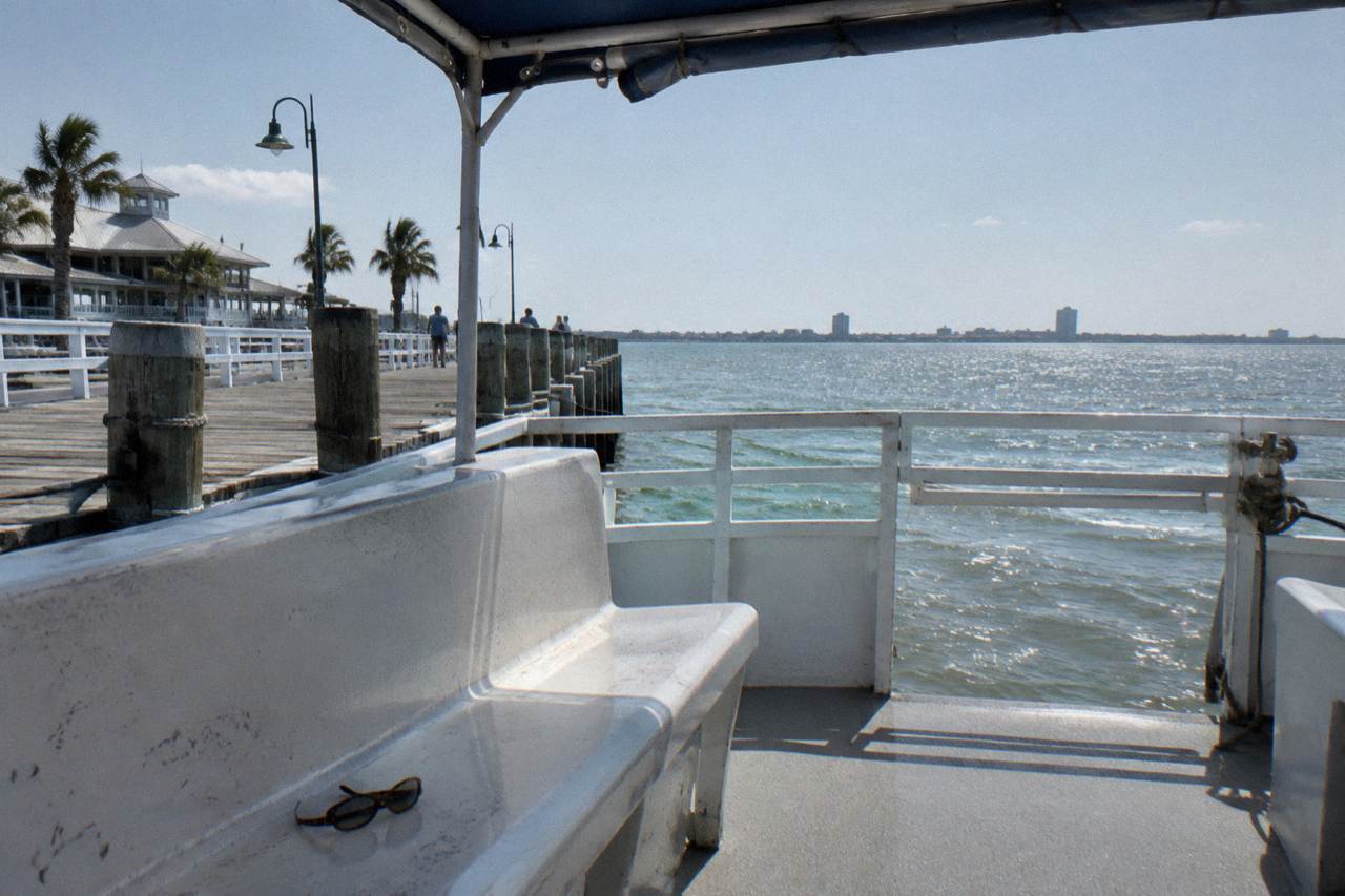 Open deck of a harbor tour boat at a wooden pier with railings and calm bay water beyond
