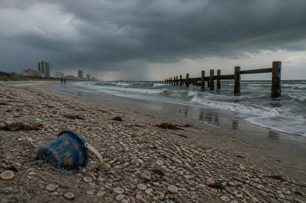 Dark storm clouds building over the Gulf horizon beyond a wooden jetty
