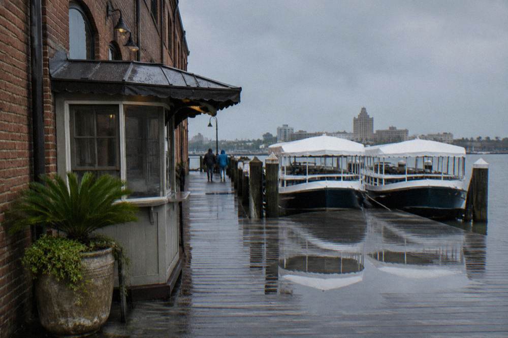 Ticket kiosk and docked tour boats at a harbor pier with hotel buildings behind