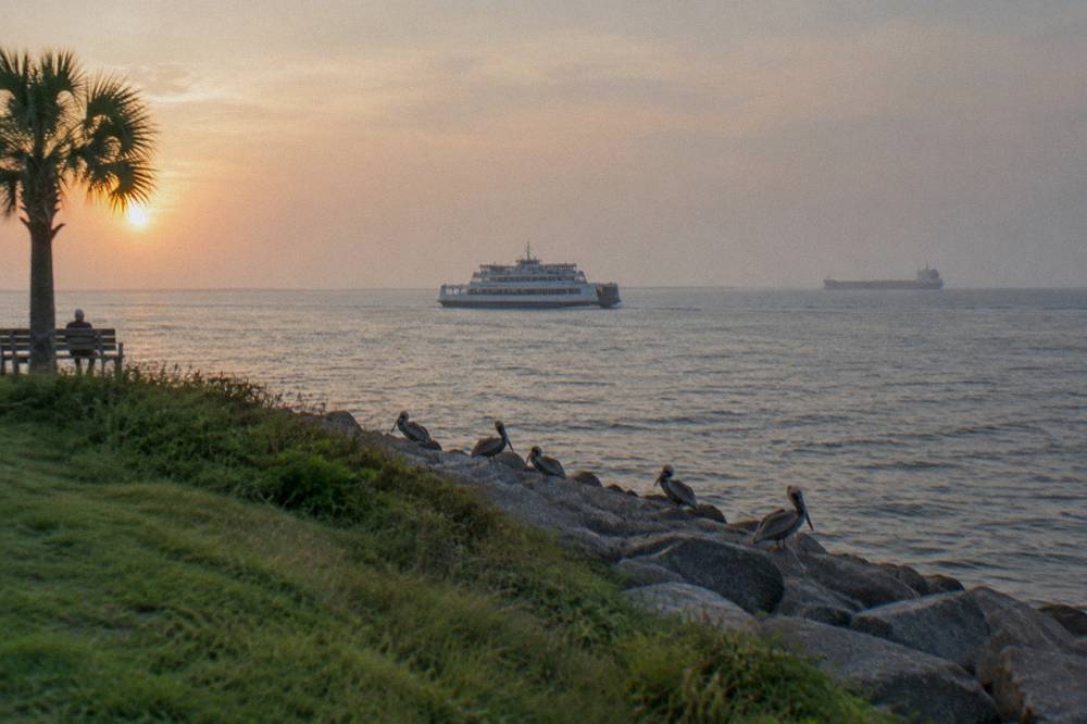 Ferry vessel crossing a ship channel with a large cargo ship in the distance