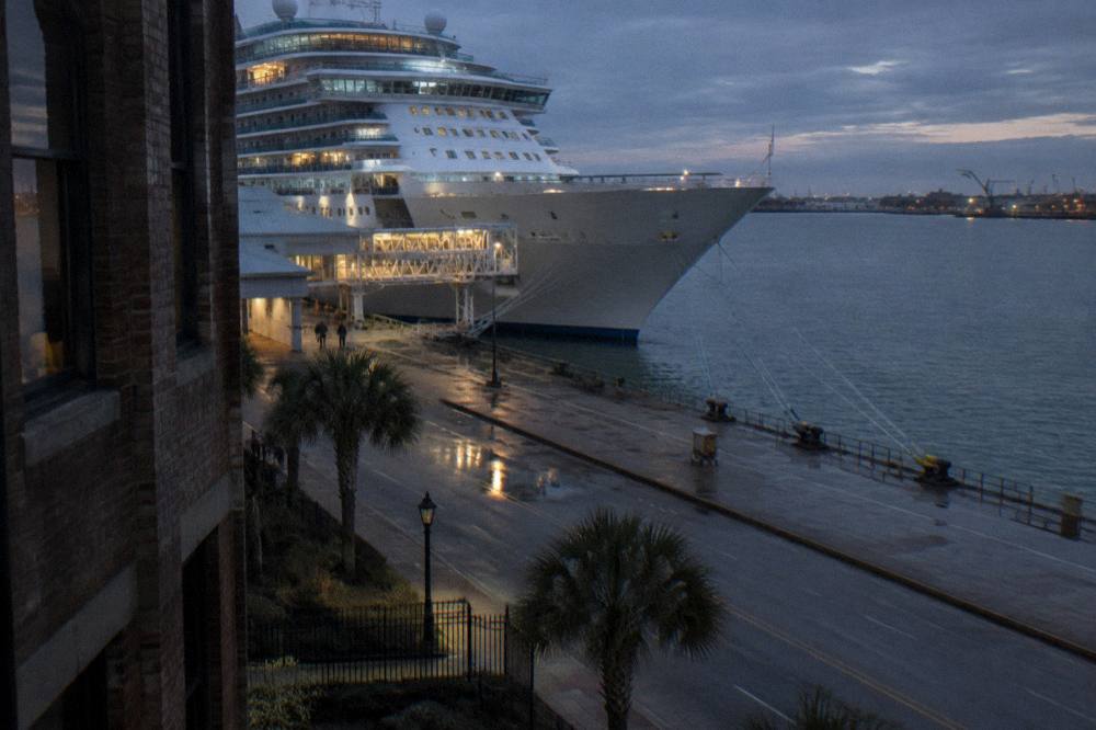 Cruise ship at berth with mooring lines and gangway visible along a terminal dock