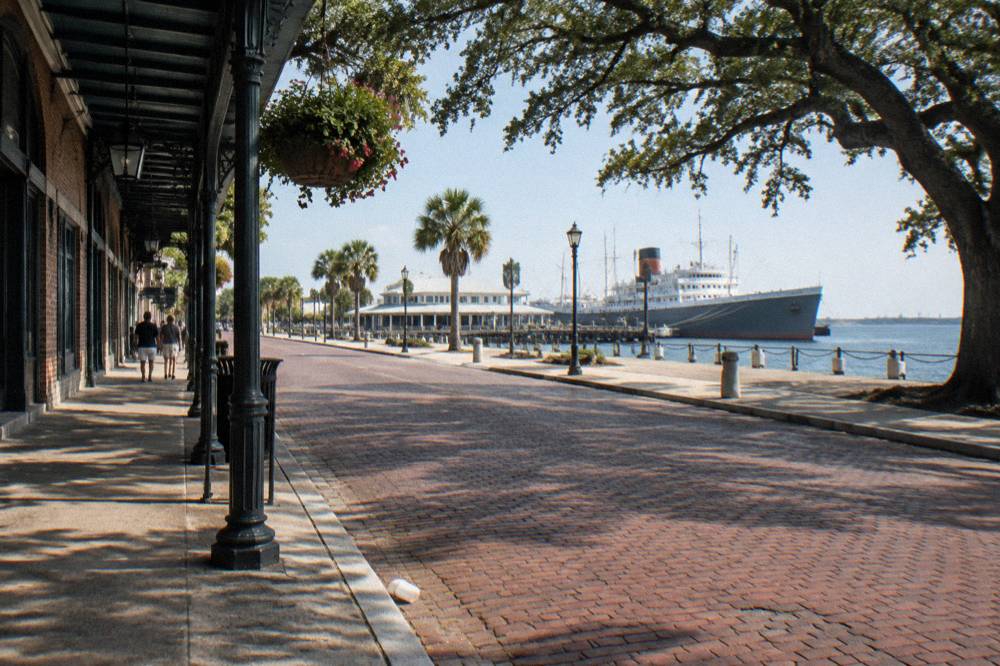 A historic brick street lined with iron-fronted nineteenth century storefronts and hanging flower baskets