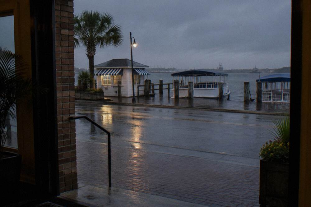 A wooden pier kiosk and moored sightseeing boats beside a hotel at a small Texas harbor