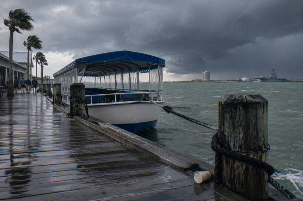 Dark storm clouds gathering over the Galveston harbor channel with a dolphin tour boat at its pier