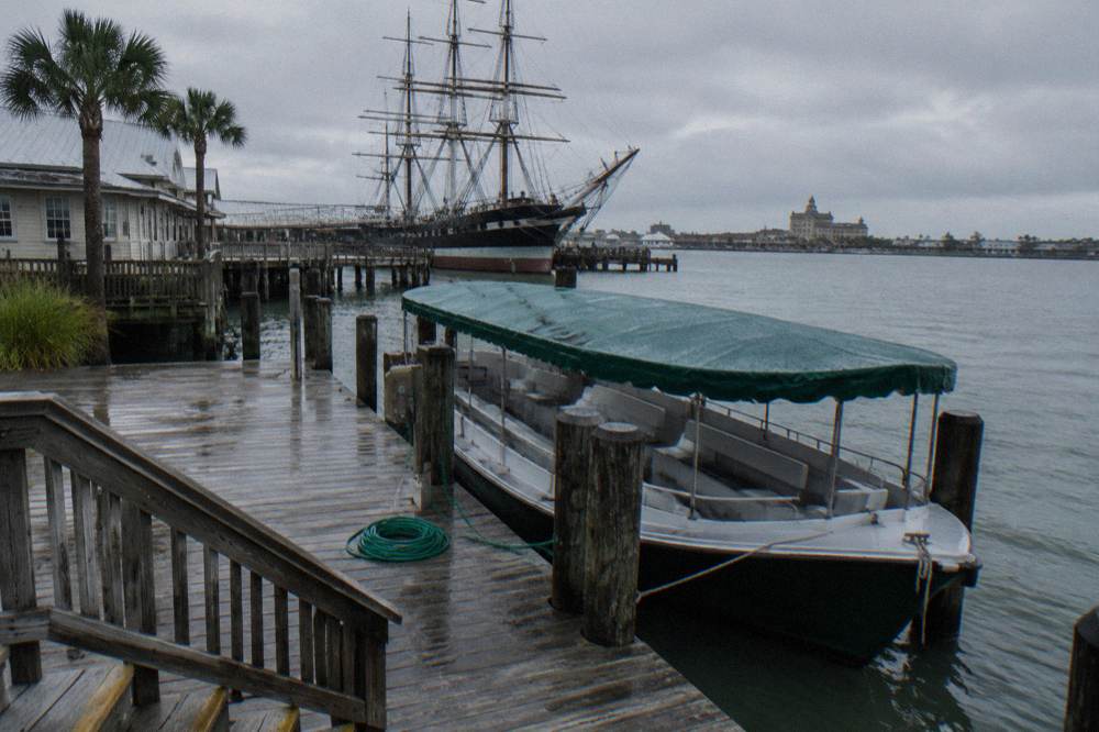 Empty covered tour boat tied up at a wooden pier under an overcast sky