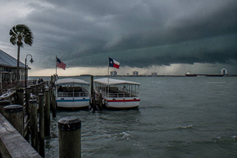 Dark clouds gathering over a harbor channel with tour boats at their pier