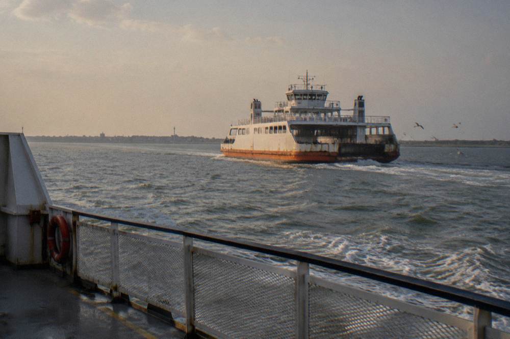 A ferry crossing a wide ship channel with open water and distant shoreline