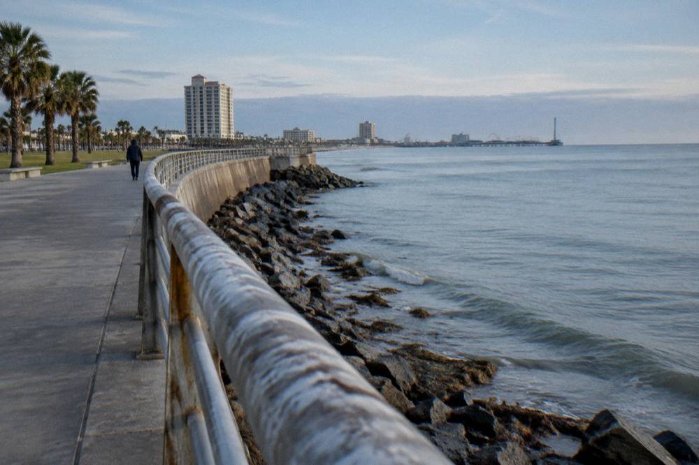 A parked bicycle and railing overlooking a calm Gulf beach in morning light